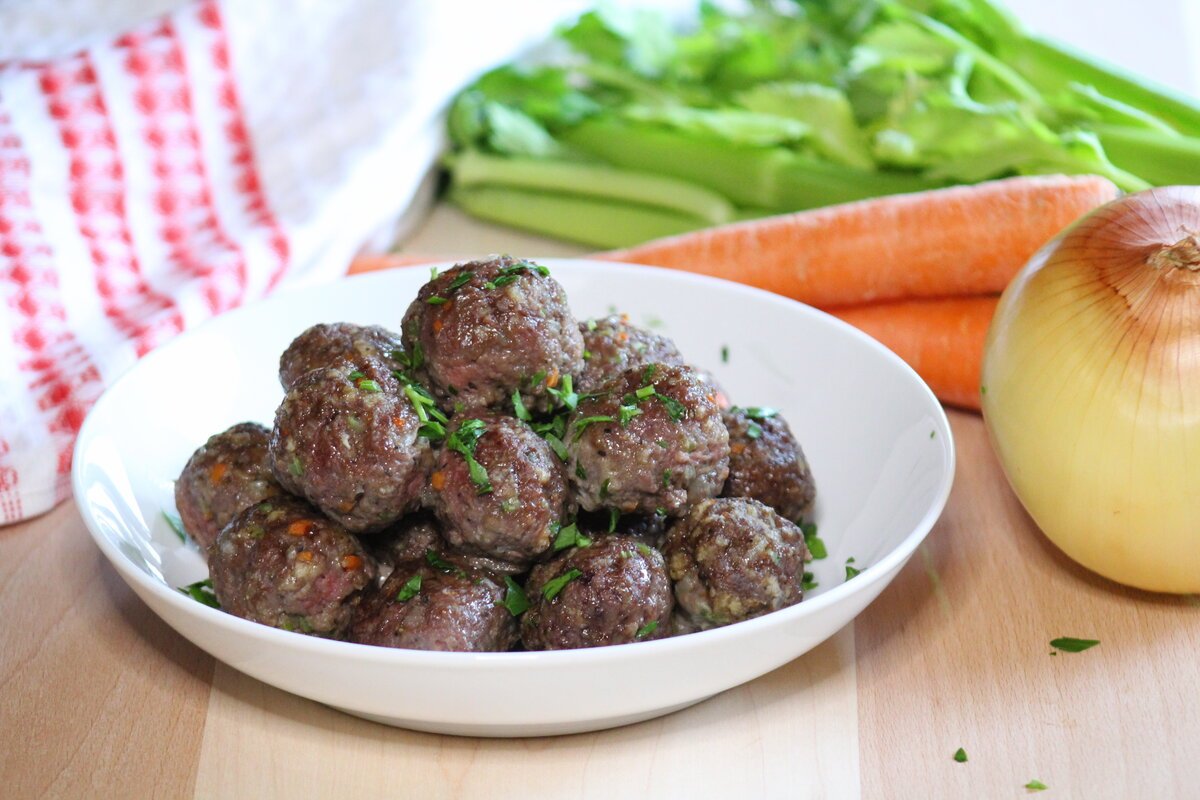 A bowl of meatballs topped with parsley.