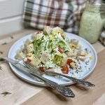 salad on a plate with silverware and dressing