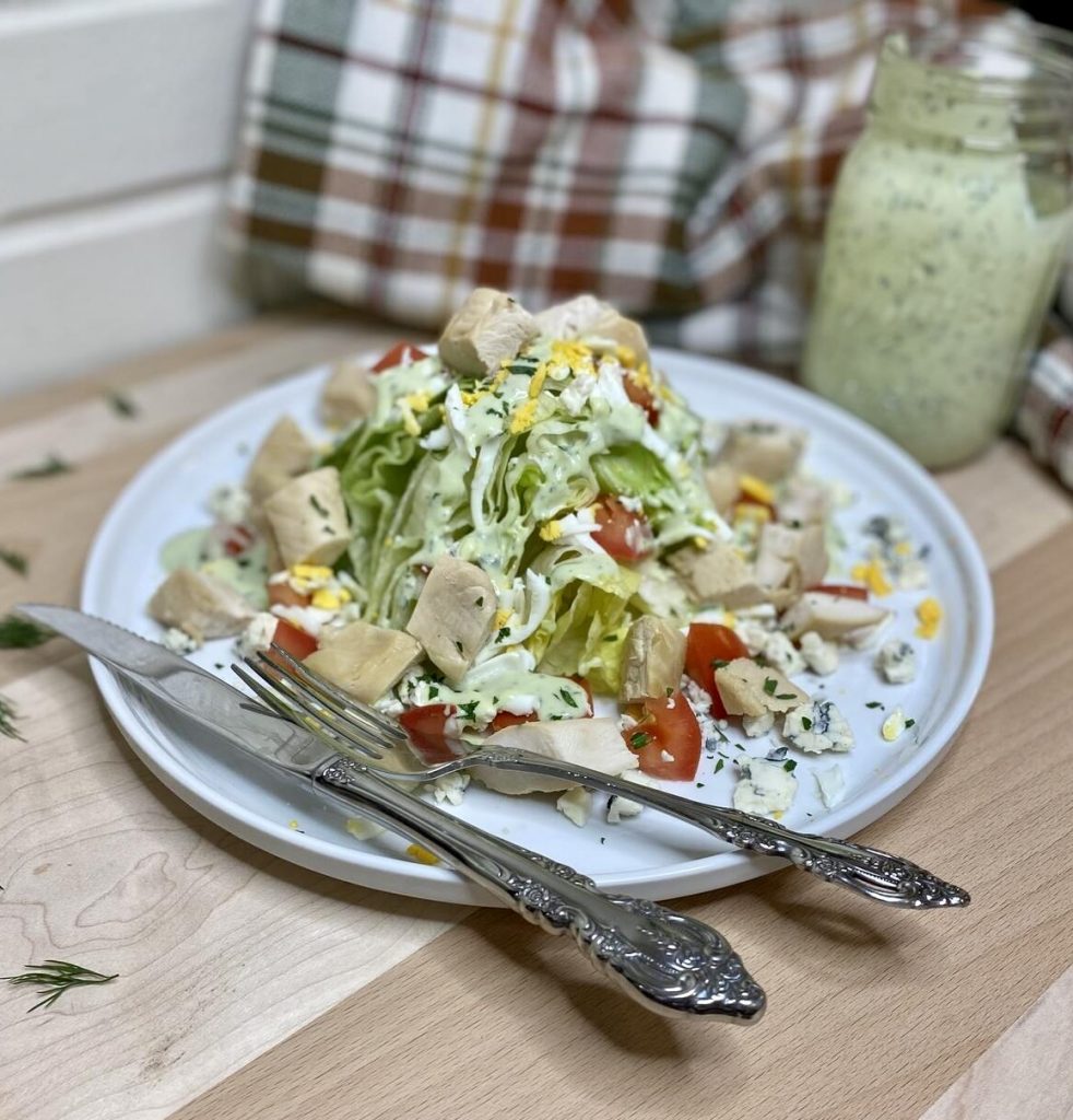 salad on a plate with silverware and dressing