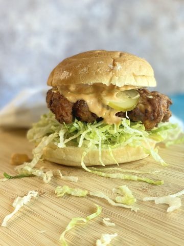 fried chicken sandwich with lettuce shreds falling off.