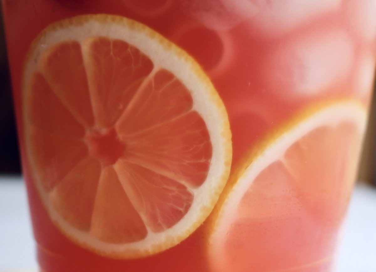 Closeup of pitcher of pink punch bubbly mocktail with floating lemons.