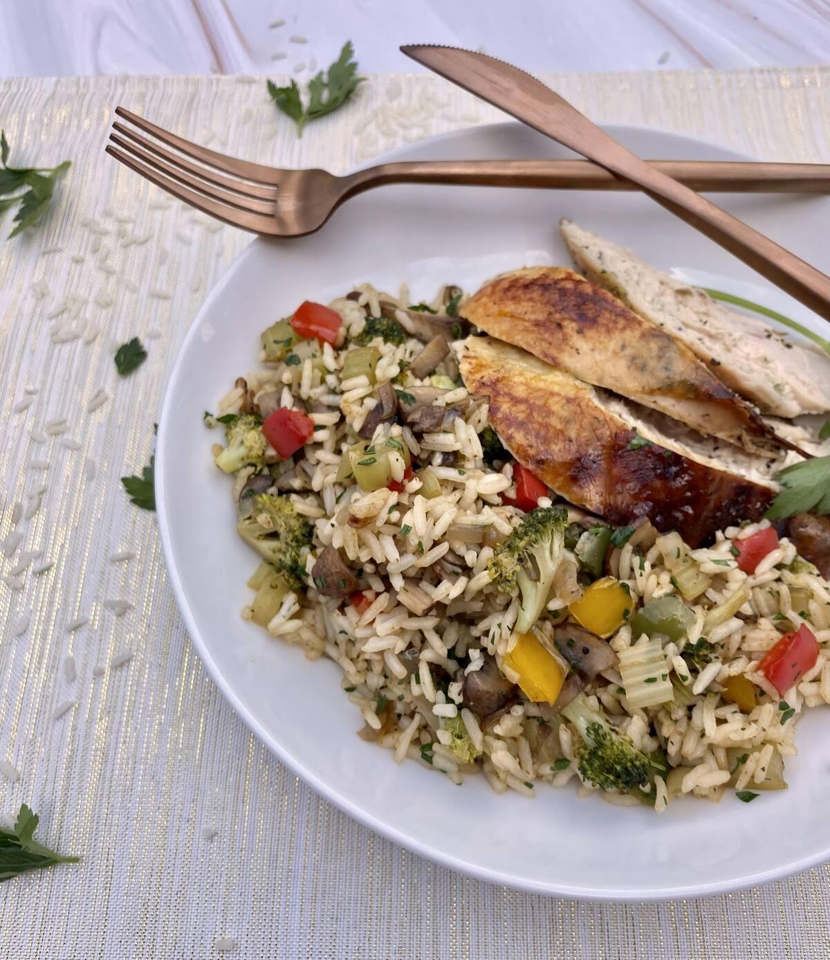 dish of garden vegetable rice with chicken and silverware.