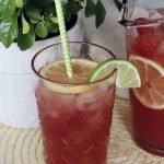 Closeup of a glass of pink bubbly punch mocktail with a straw.