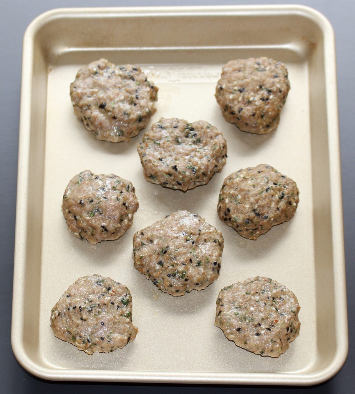 Cooked thai-inspired pork patties on a sheetpan.