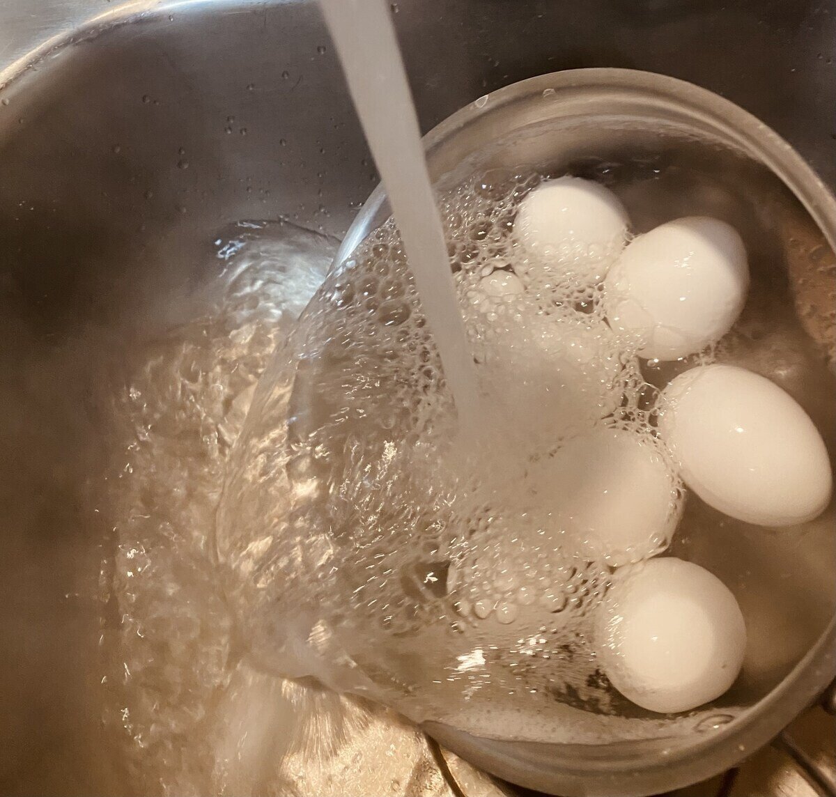 Rinsing hardboiled eggs under cold water.