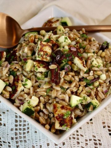 Bowl of Farro, Corn, and Zucchini Salad with Fried Cheese with a spoon.