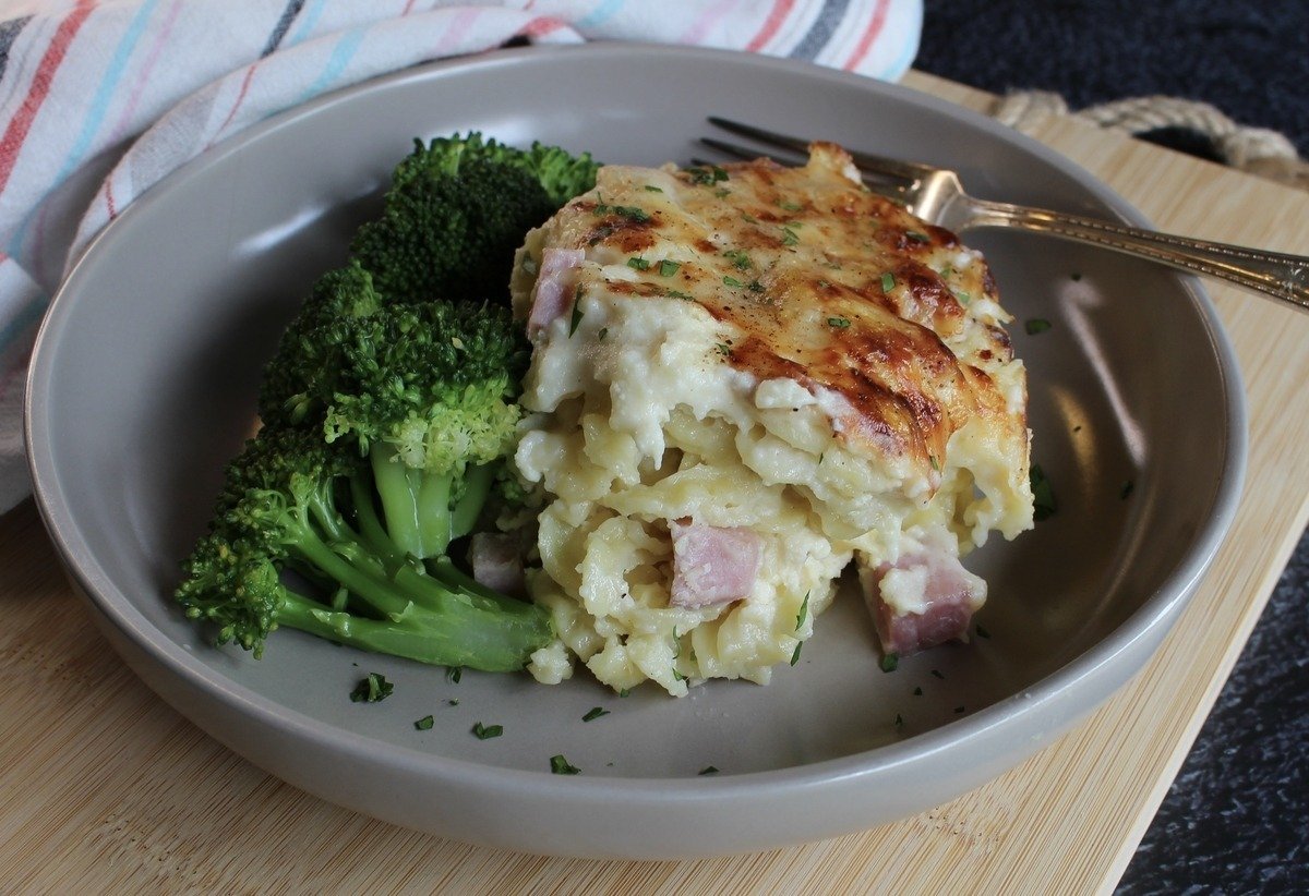 Croque monsieur pasta bake sliced into a dish with a side of broccoli.