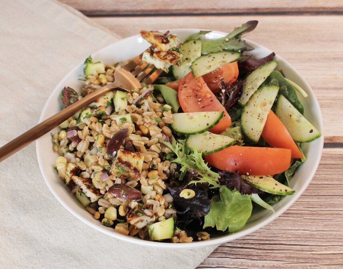 A bowl of farro salad with a green salad and a fork.