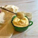 green dish of garlic aioli and a spoon.