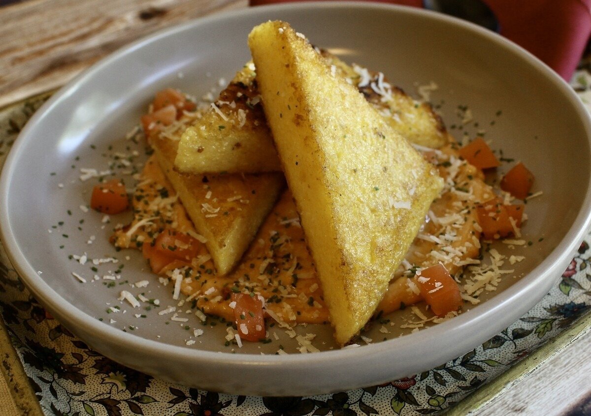 Fried polenta in a dish with aioli and parmesan shreds.