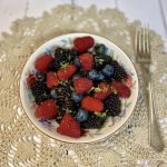 A bowl of summer berries with lime zest and a fork.