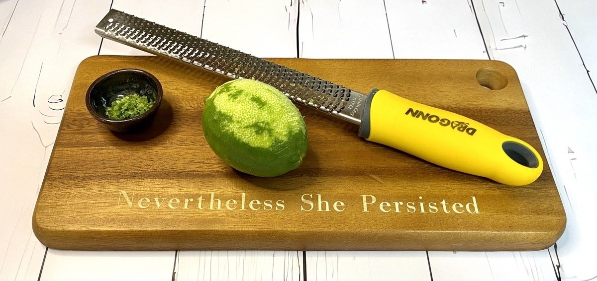 Cutting board with microplaning tool zesting a lime.