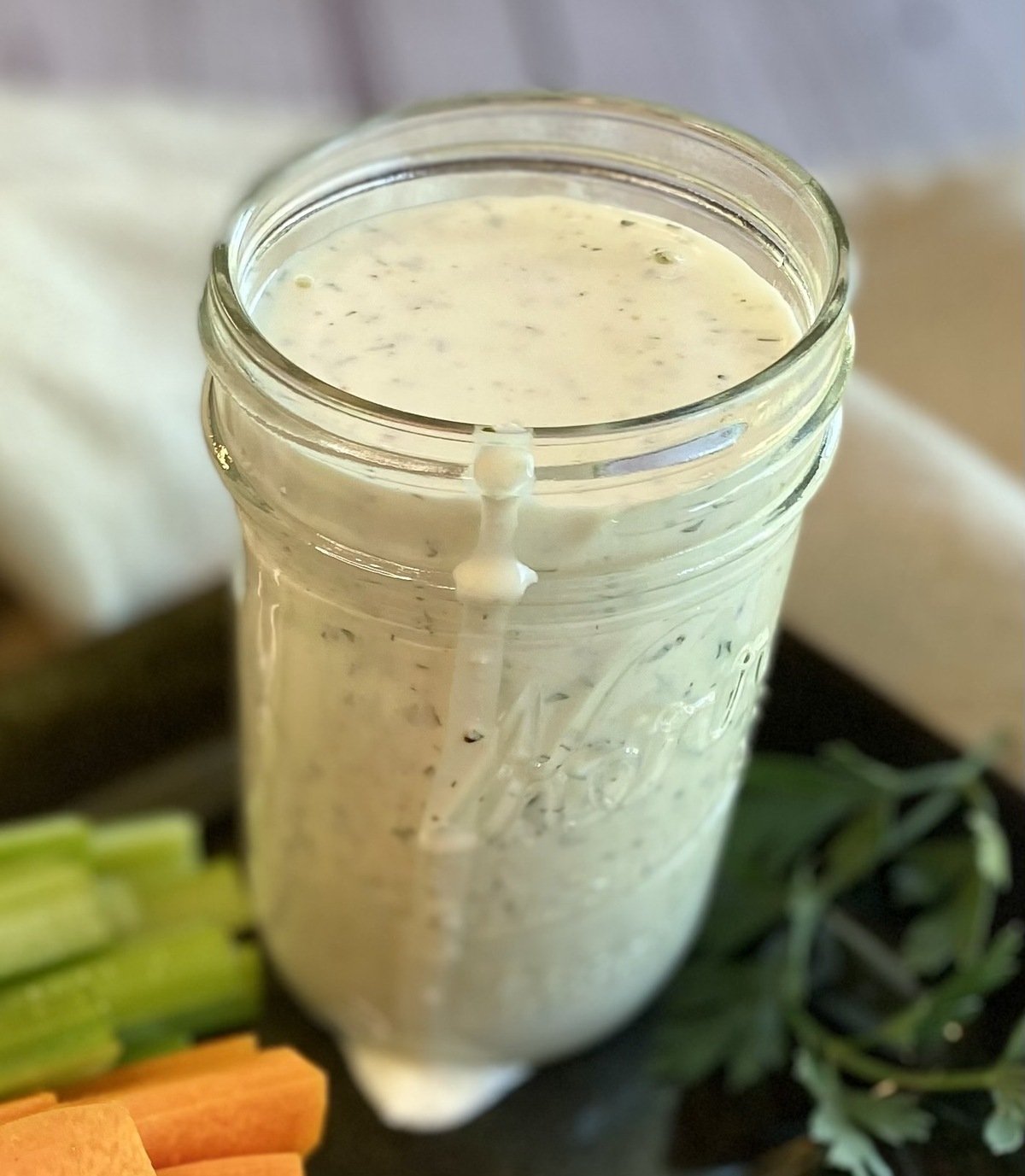 A mason jar of the best homemade ranch dressing with a drip falling down the side.