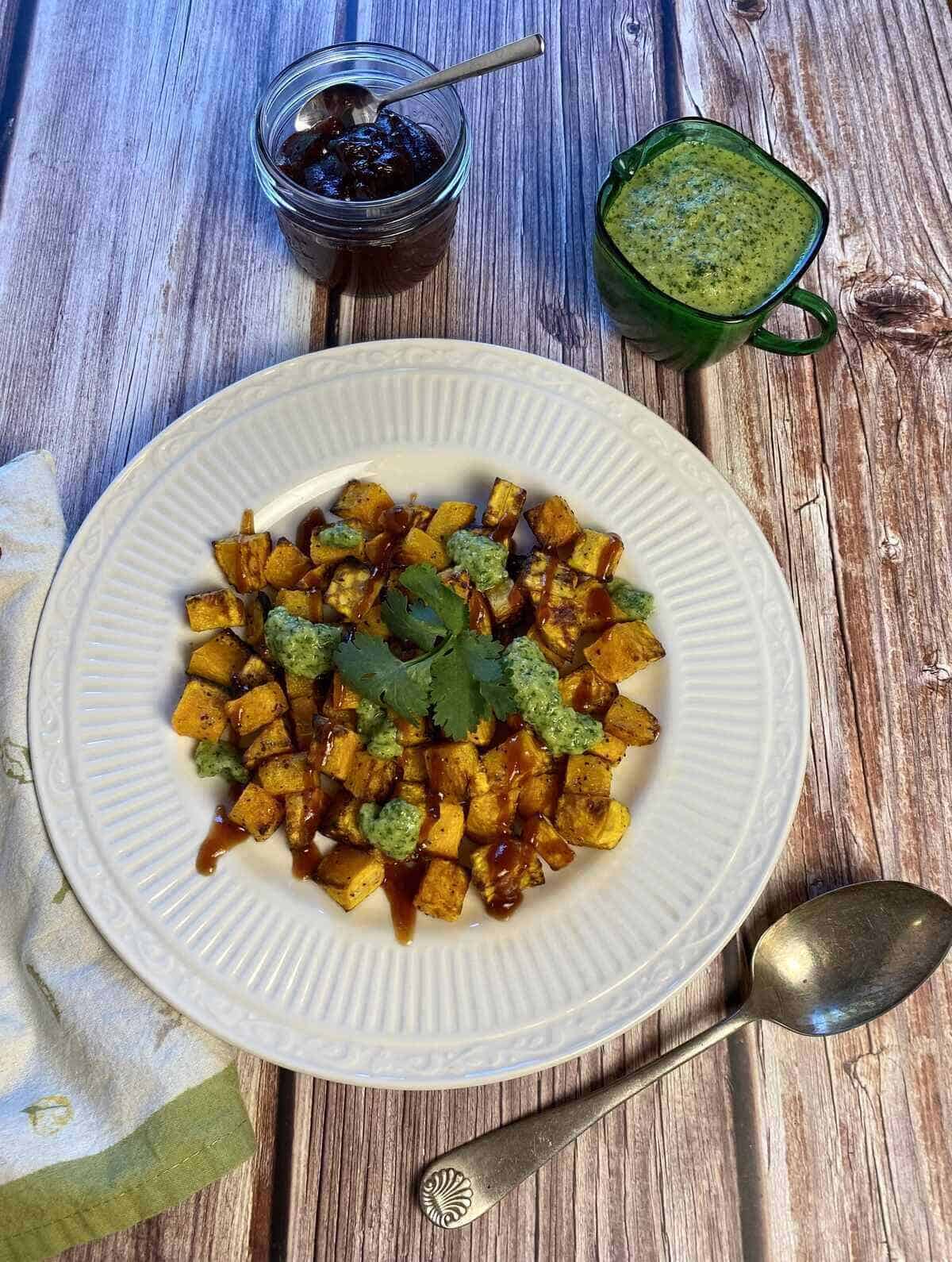 A serving dish with the dressed squash, both sauces, and a serving spoon.