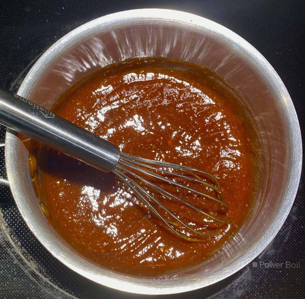 The bbq sauce ingredients whisked together in a small pot on the stove.