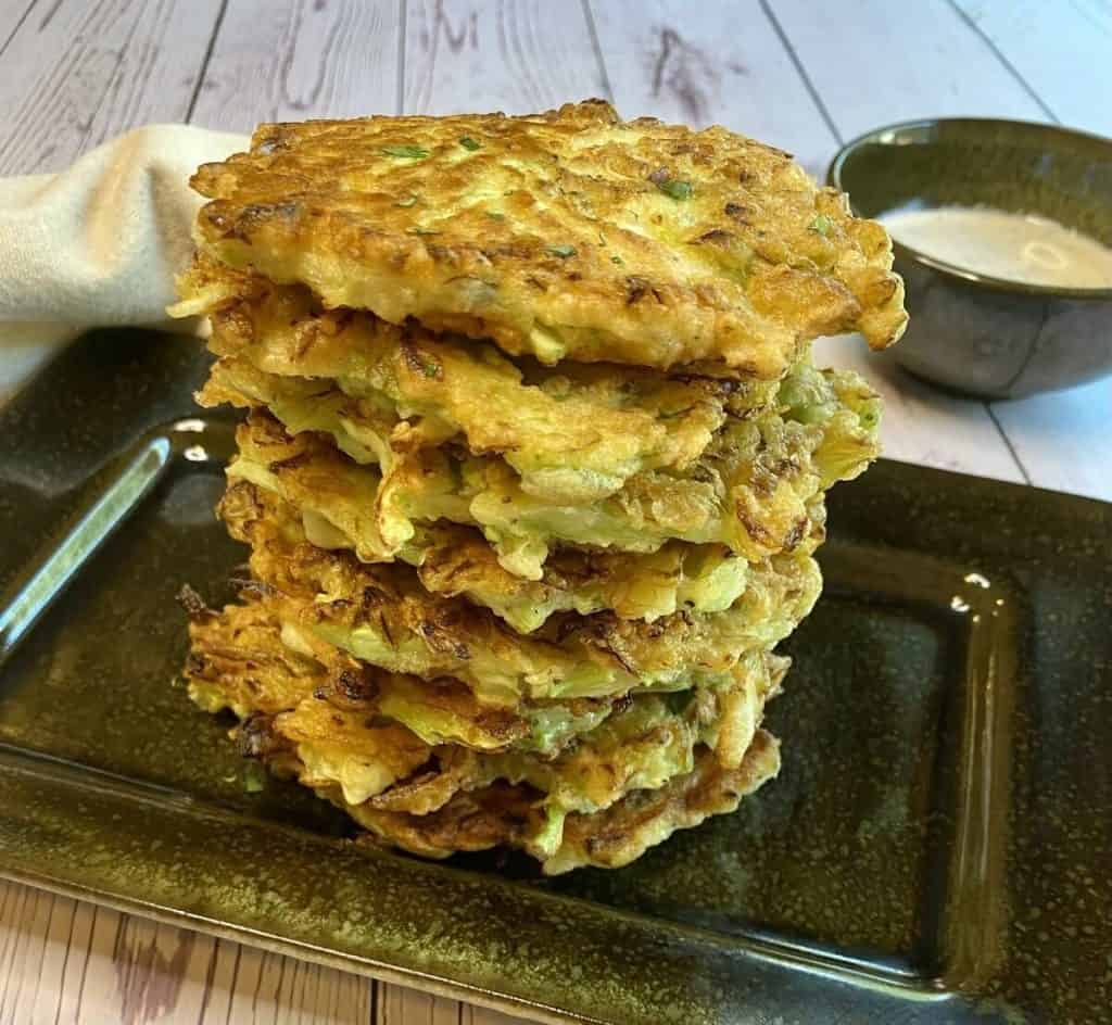 Cabbage fritters stacked up high with a dipping sauce nearby.