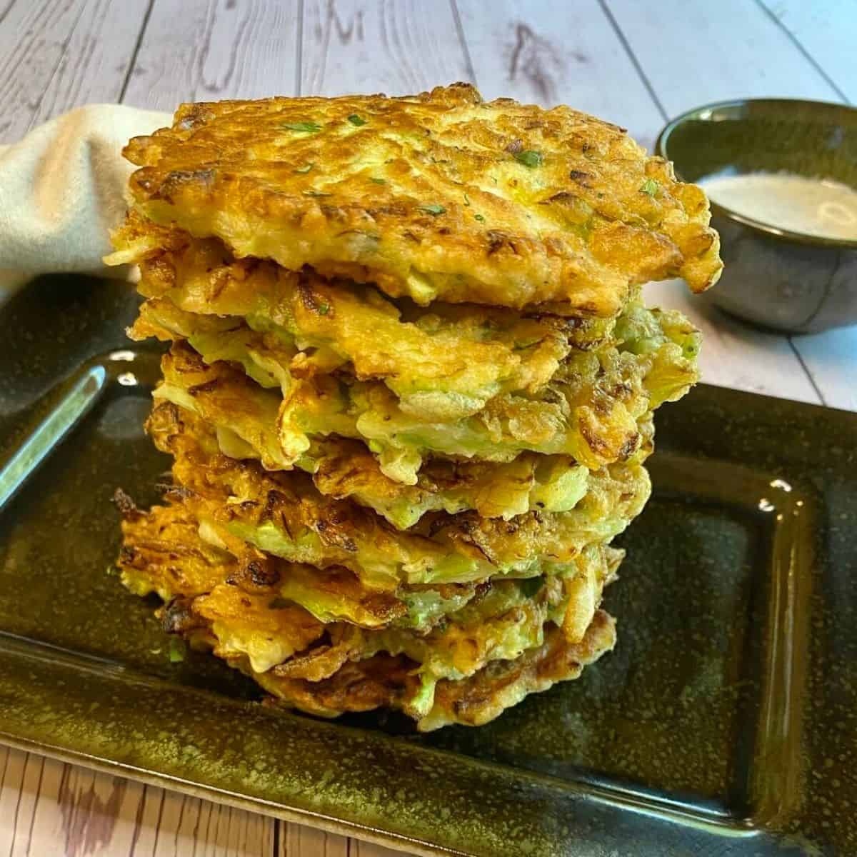 A stack of cabbage fritters on a black plate.