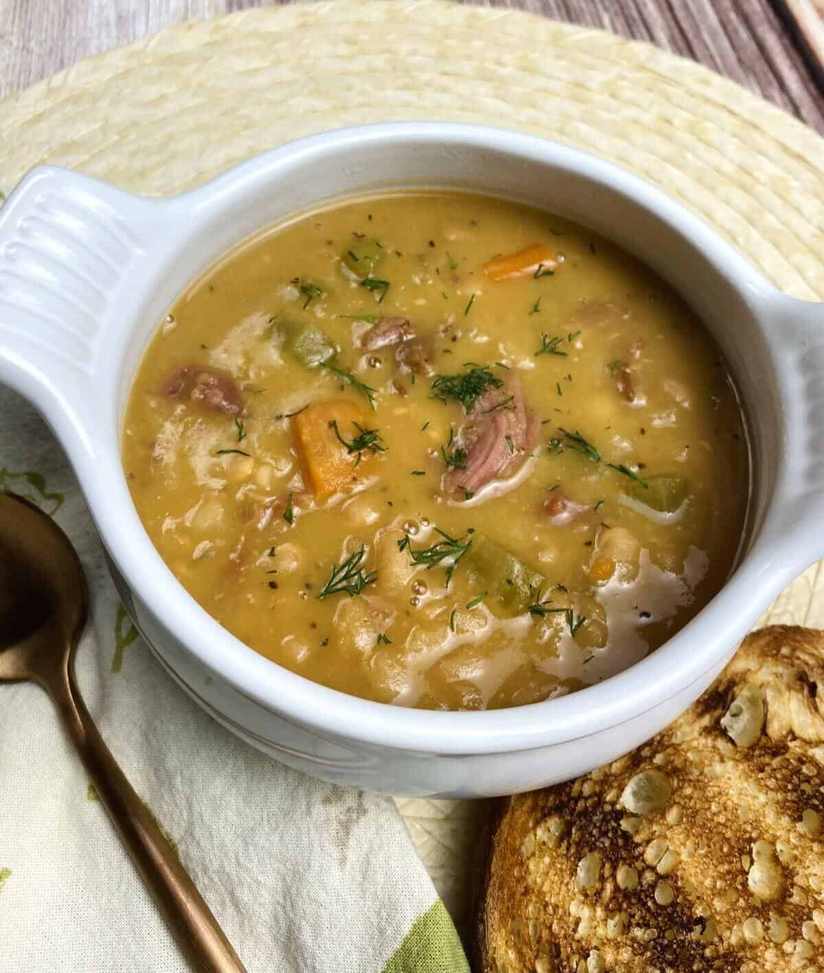 A closeup of the ham and bean soup with a piece of toast.