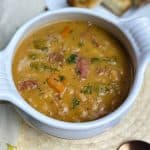 A white bowl filled with ham and beans with toast.