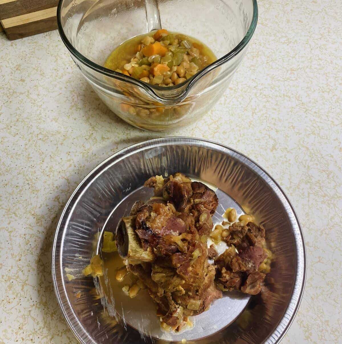 A pitcher with some of the beans and a pan with the cooked hambone.