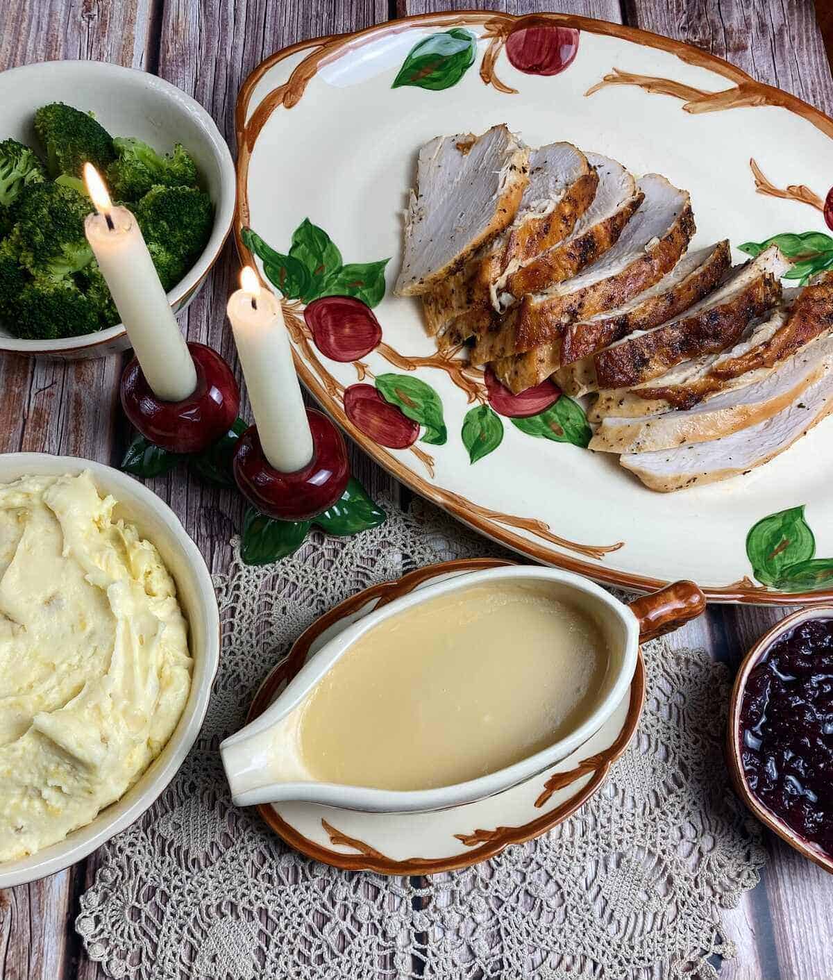 A Thanksgiving spread with turkey, potatoes, cranberries, broccoli and gravy in the middle.