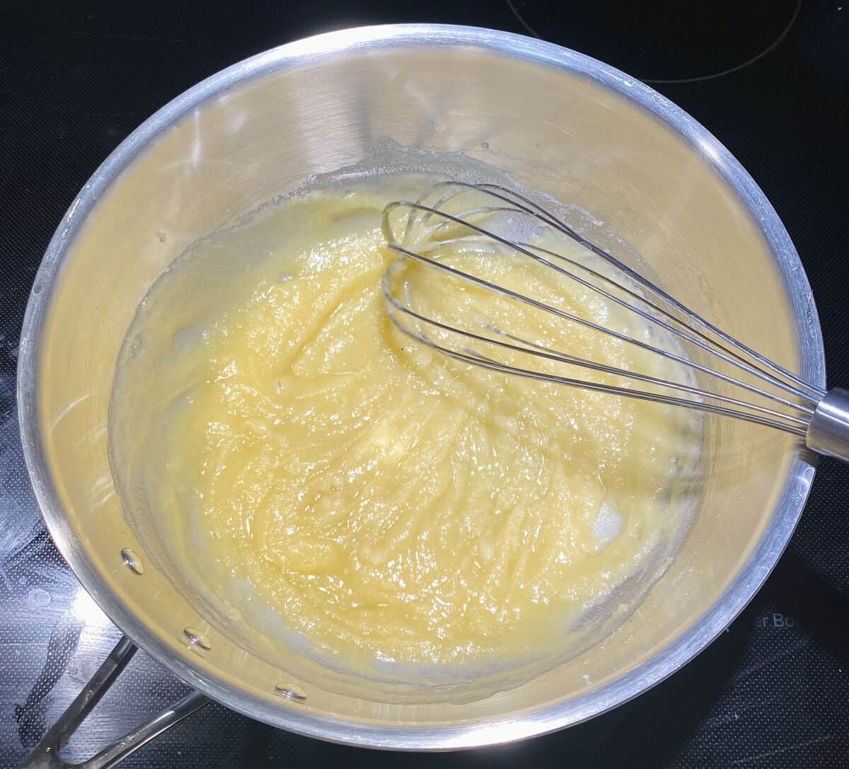 Flour whisked into melted butter in a pot on the stove to create a roux.