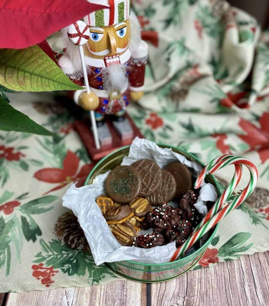 3 easy christmas treats in a christmas tin with candy canes alongside a sparkly nutcracker.