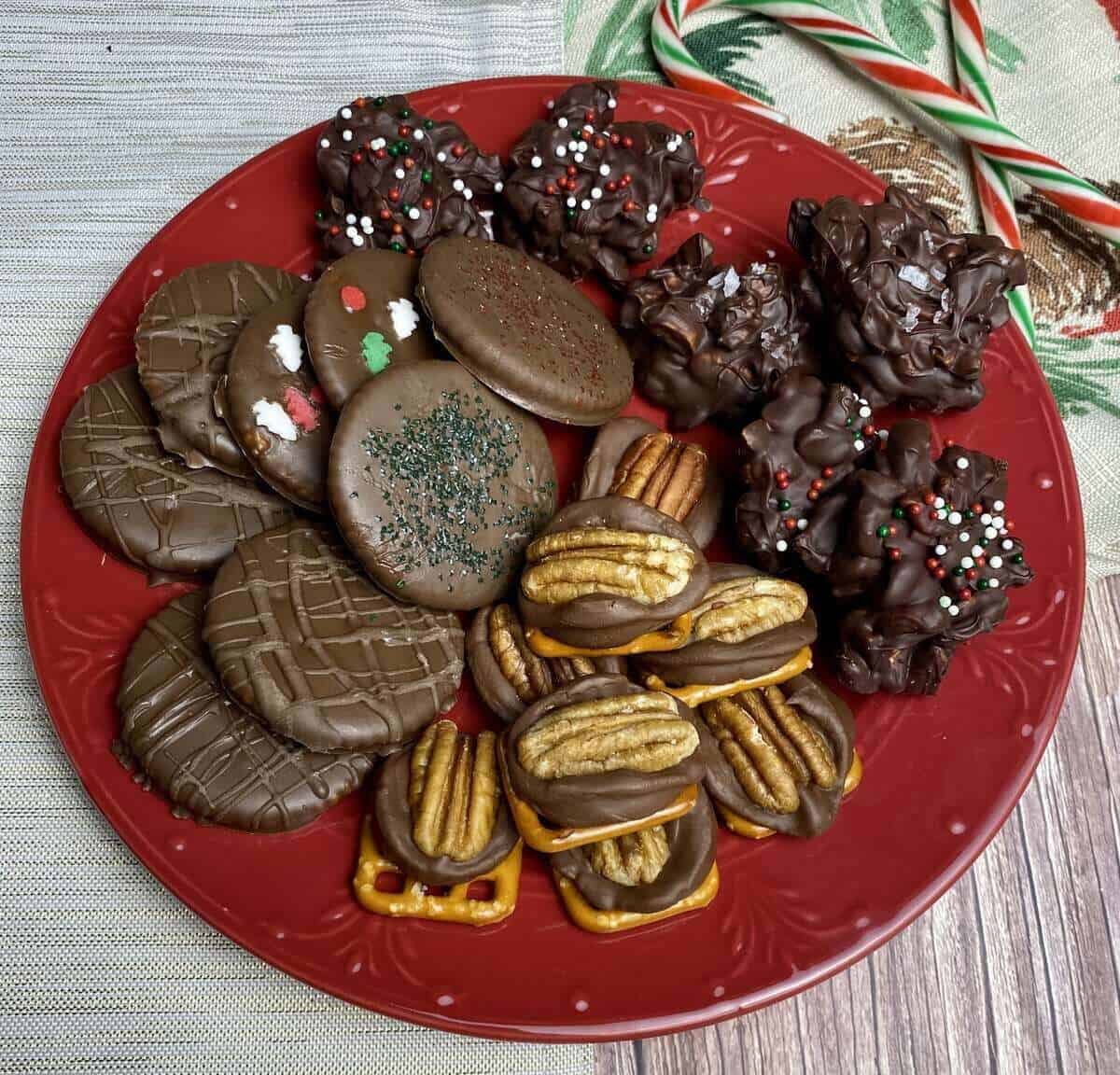 Three kinds of chocolates on a red plate with candy canes in the background.