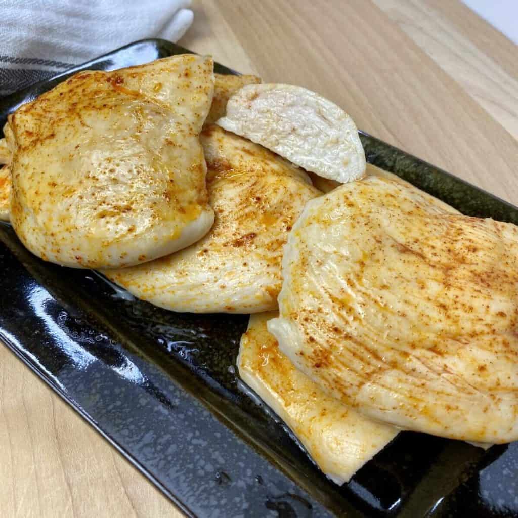 A plate with cooked baked thin sliced chicken breast.