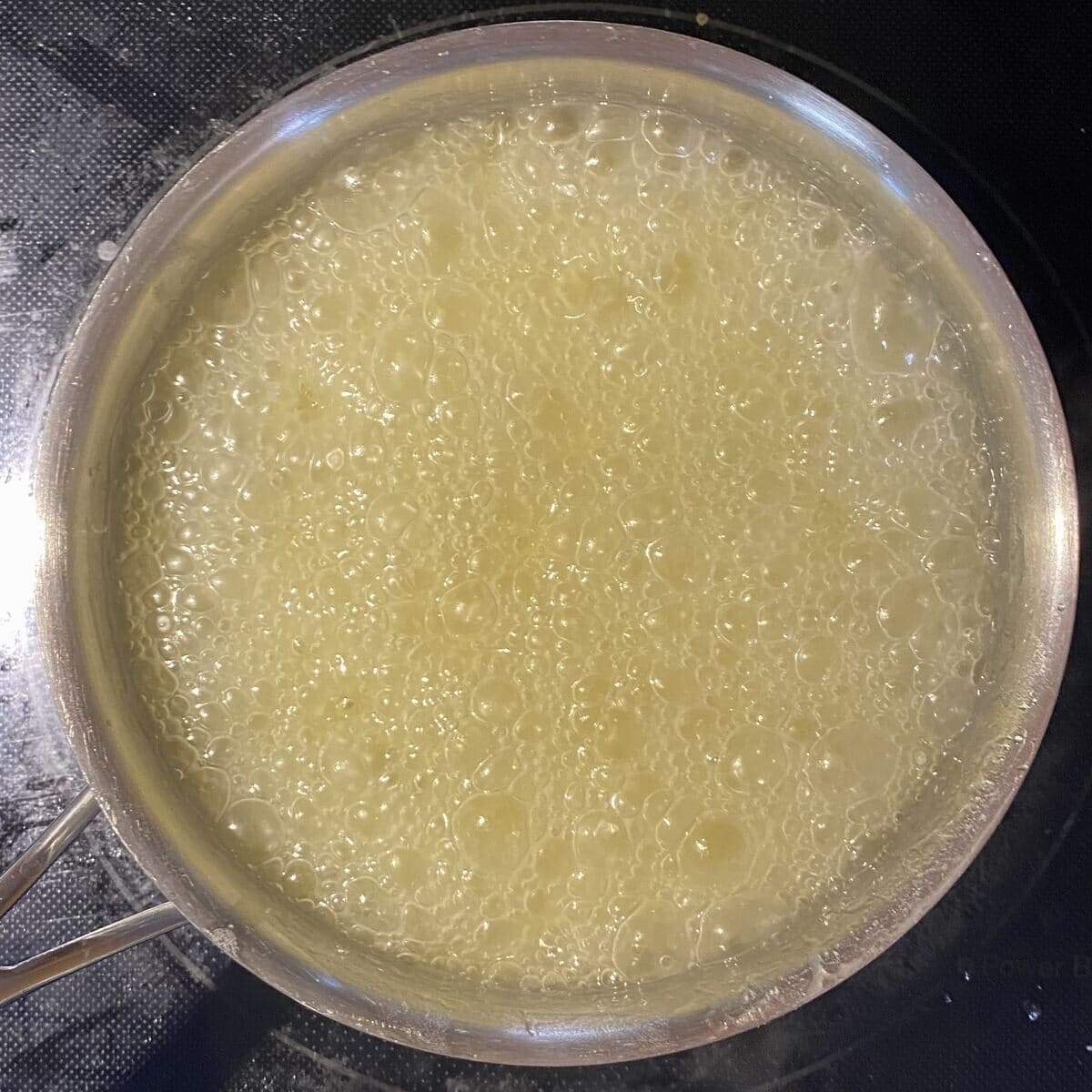 A 1 quart pot on the stove showing the sugar and butter mixture boiling.