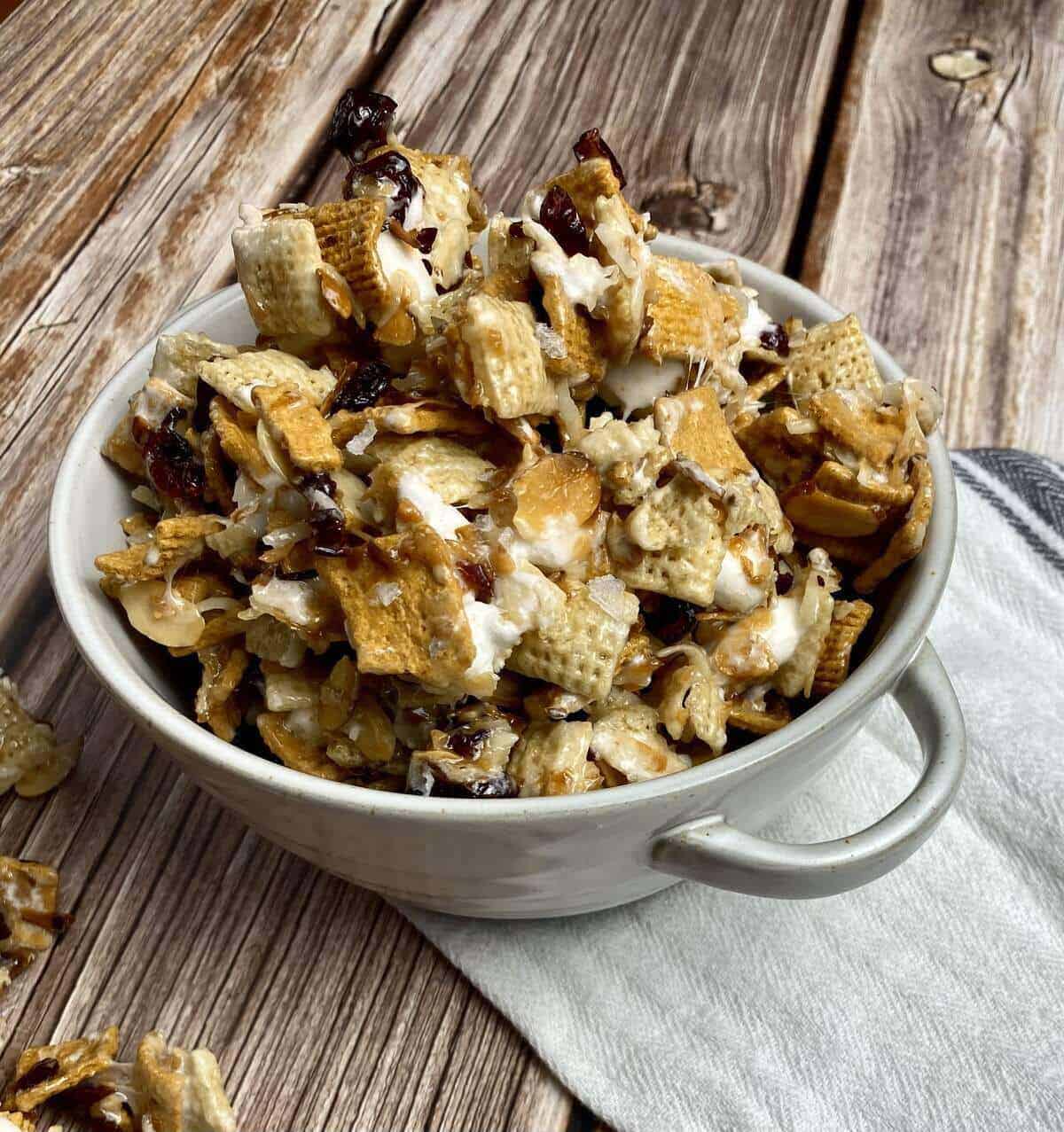 A bowl of coconut c
raisin crunch piled high alongside a fabric napkin and extra pieces of candy on the table.