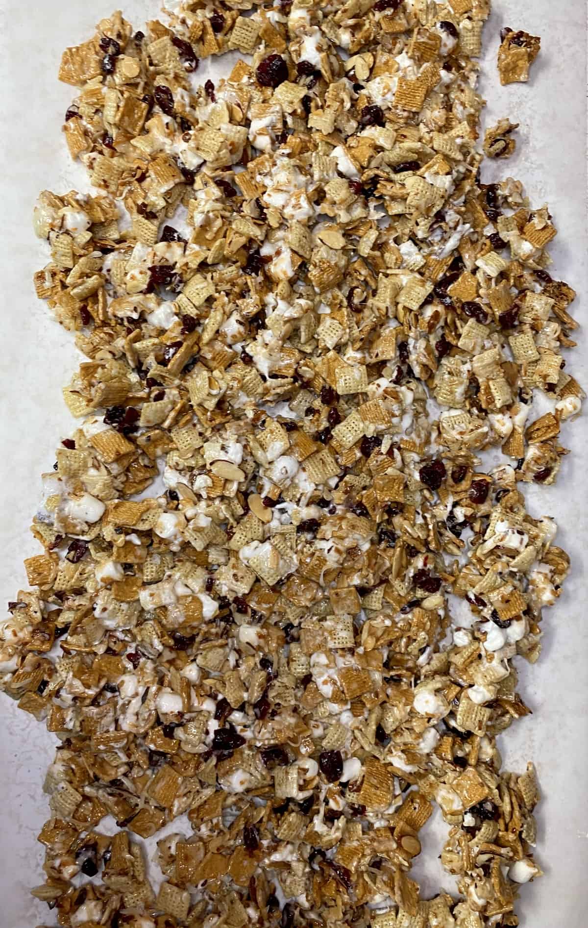 The entire batch of craisin crunch dumped out onto parchment paper to cool.