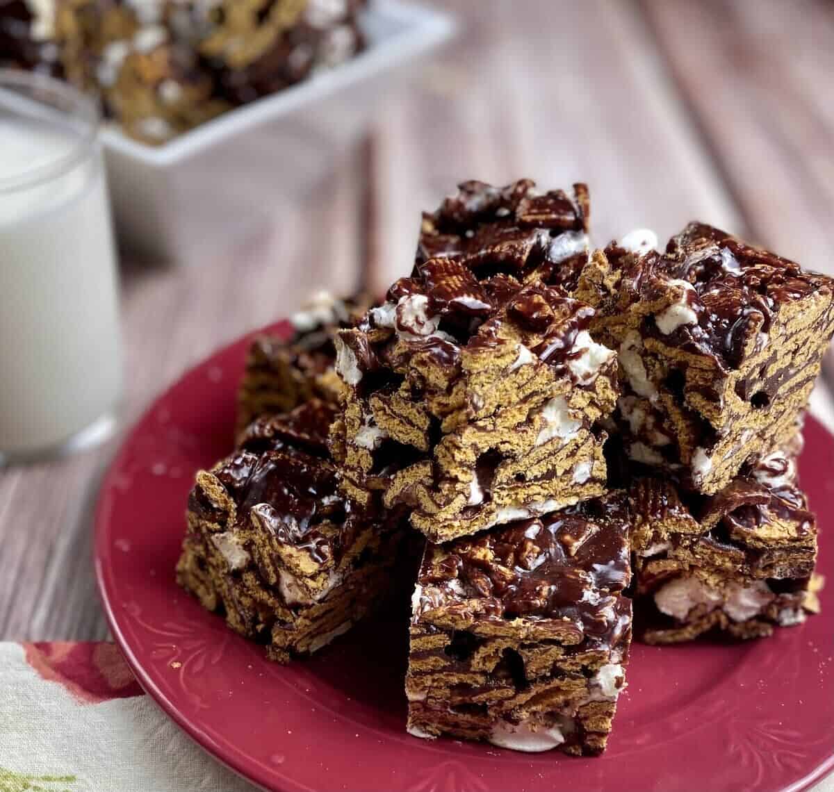 A red plate with treats piled on top with a white bowl filled with. more treats and a glass of milk.