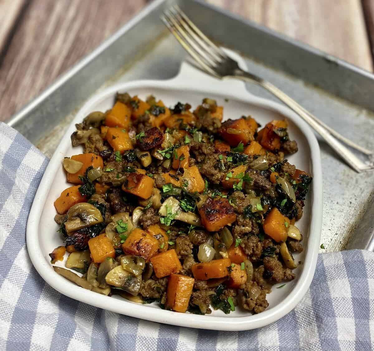 A plate of hash on a metal tray with a napkin and fork.