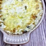 Baked crab and spinach dip in a dish on a table.