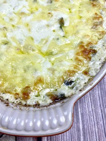 Baked crab and spinach dip in a dish on a table.