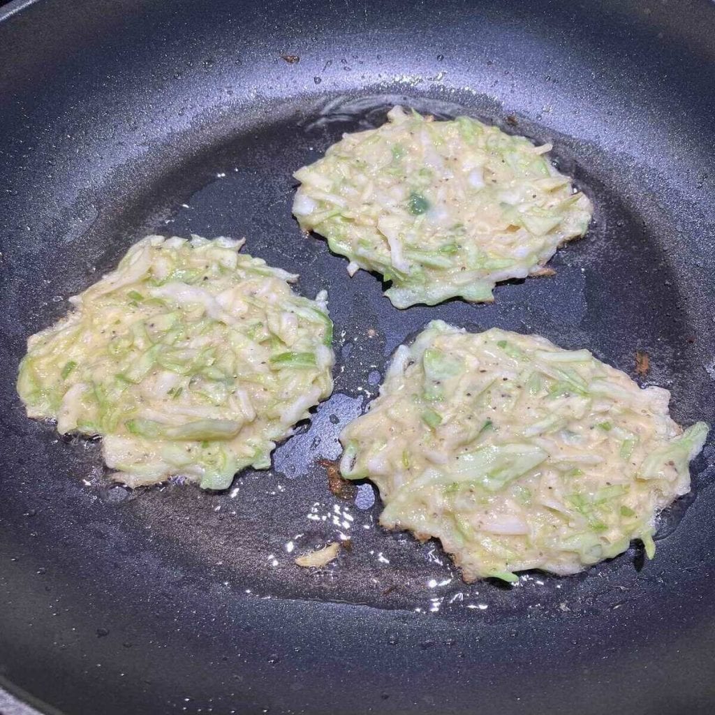 A close up of the batter dosed into a frying pan with oil.