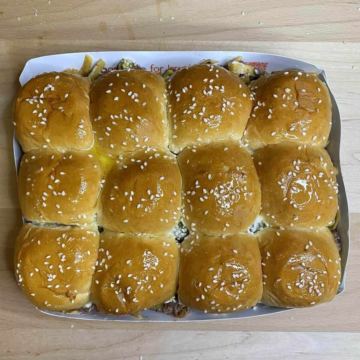 The assembled cheeseburger sliders with melted butter on top and sesame seeds.