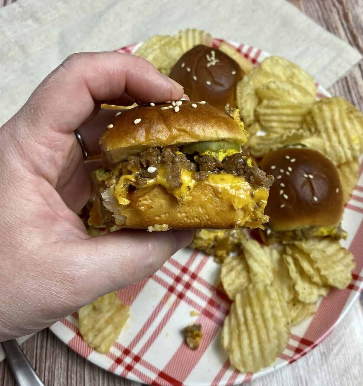 A hand holding up a burger showing the ingredients layers from the side.