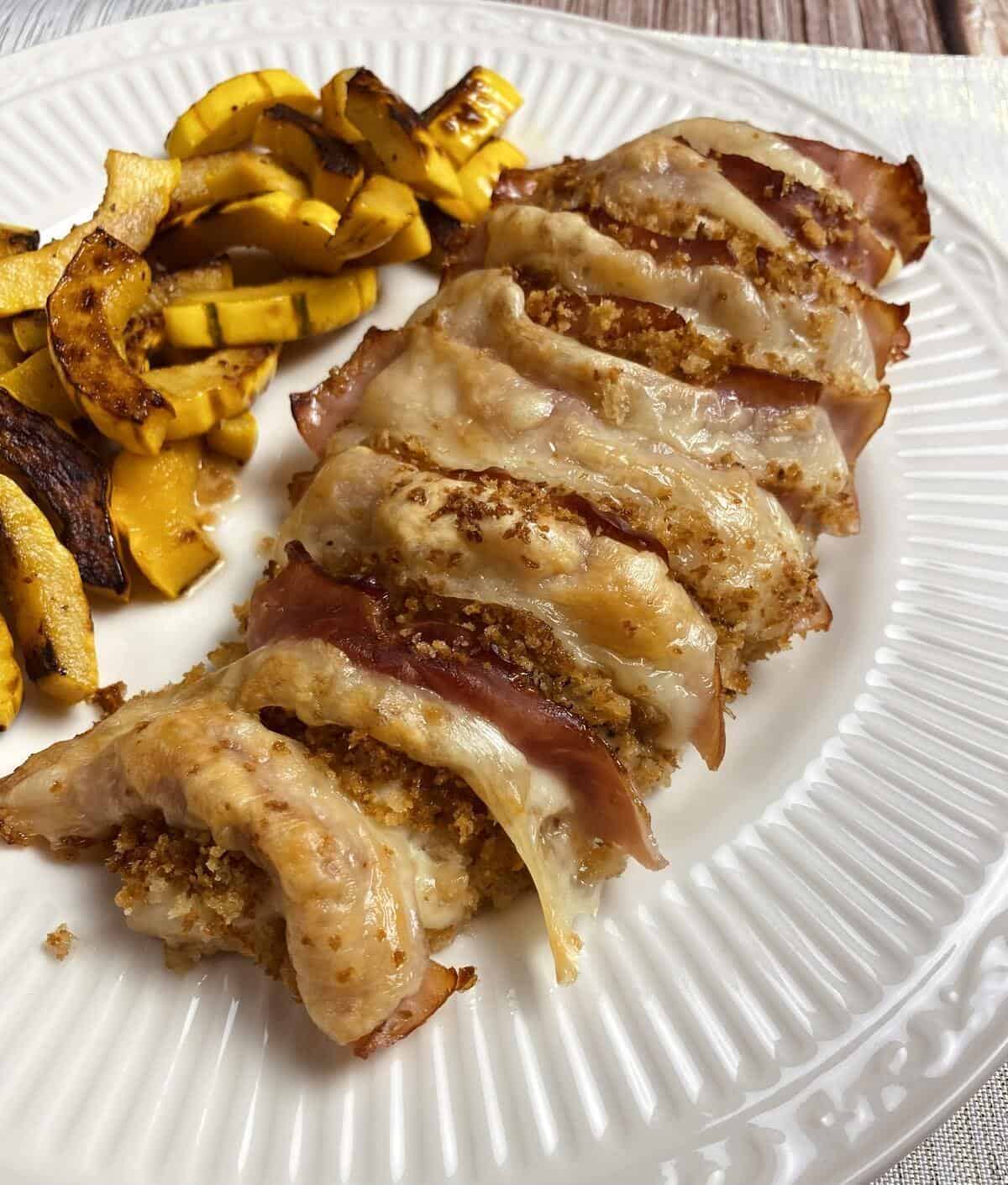 A dinner plate with chicken cordon bleu and sliced sauteed squash.