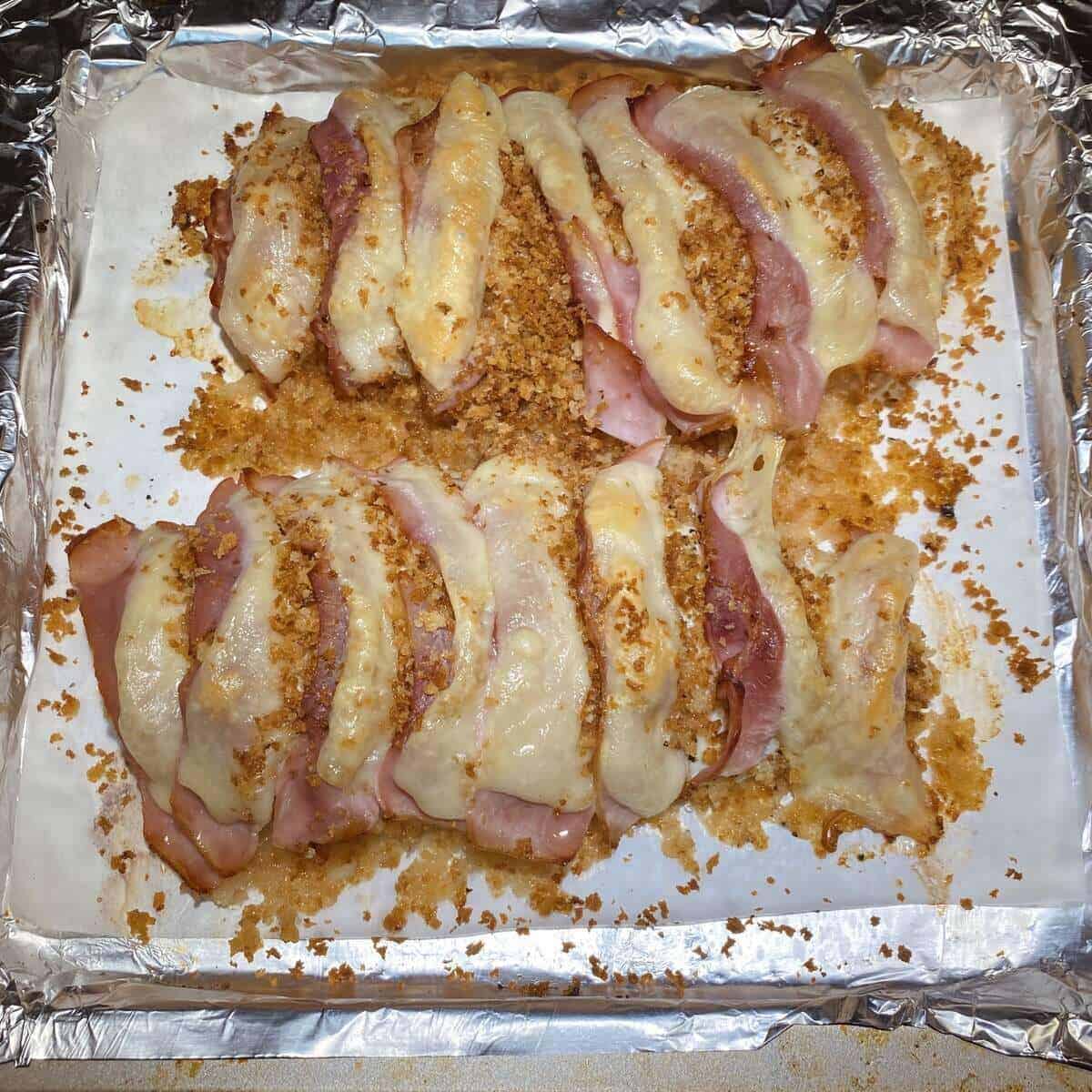 Two prepared chicken breasts after they've been roasted and the cheese is melting on top.