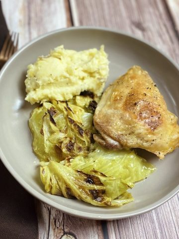 Feature photo of fried chicken thighs on schmaltzy cabbage.