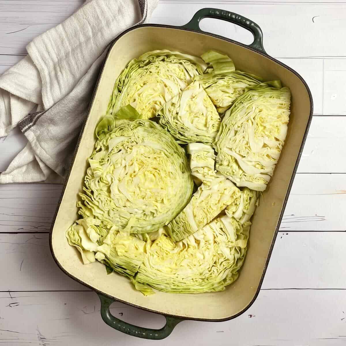 Uncooked cabbage sliced thick and wedged into a dish before cooking.