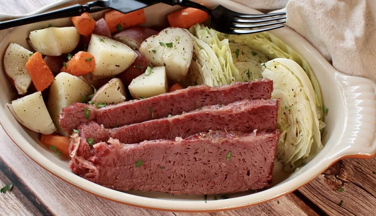 A dish of roasted corned beef and vegetables with a napkin.