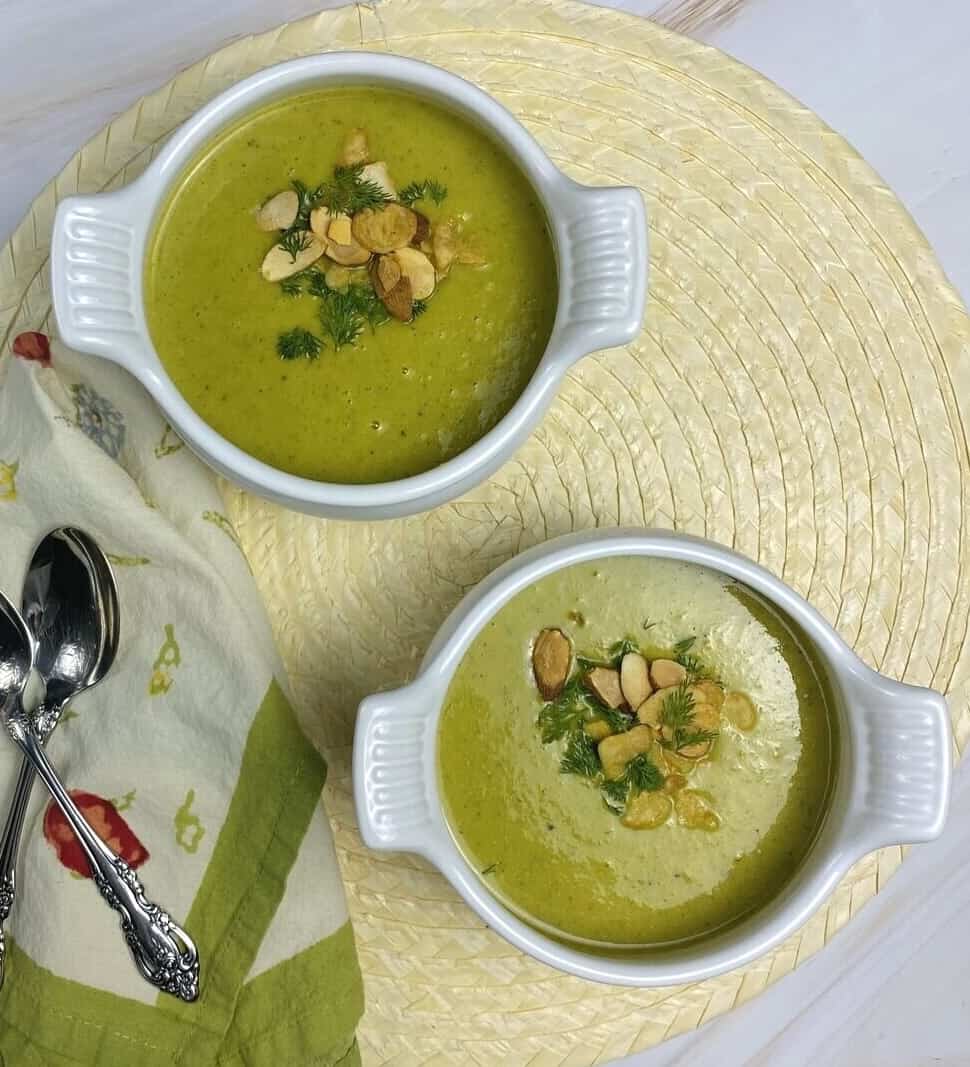 Two bowls on a placemat with soup alongside spoons and a napkin.