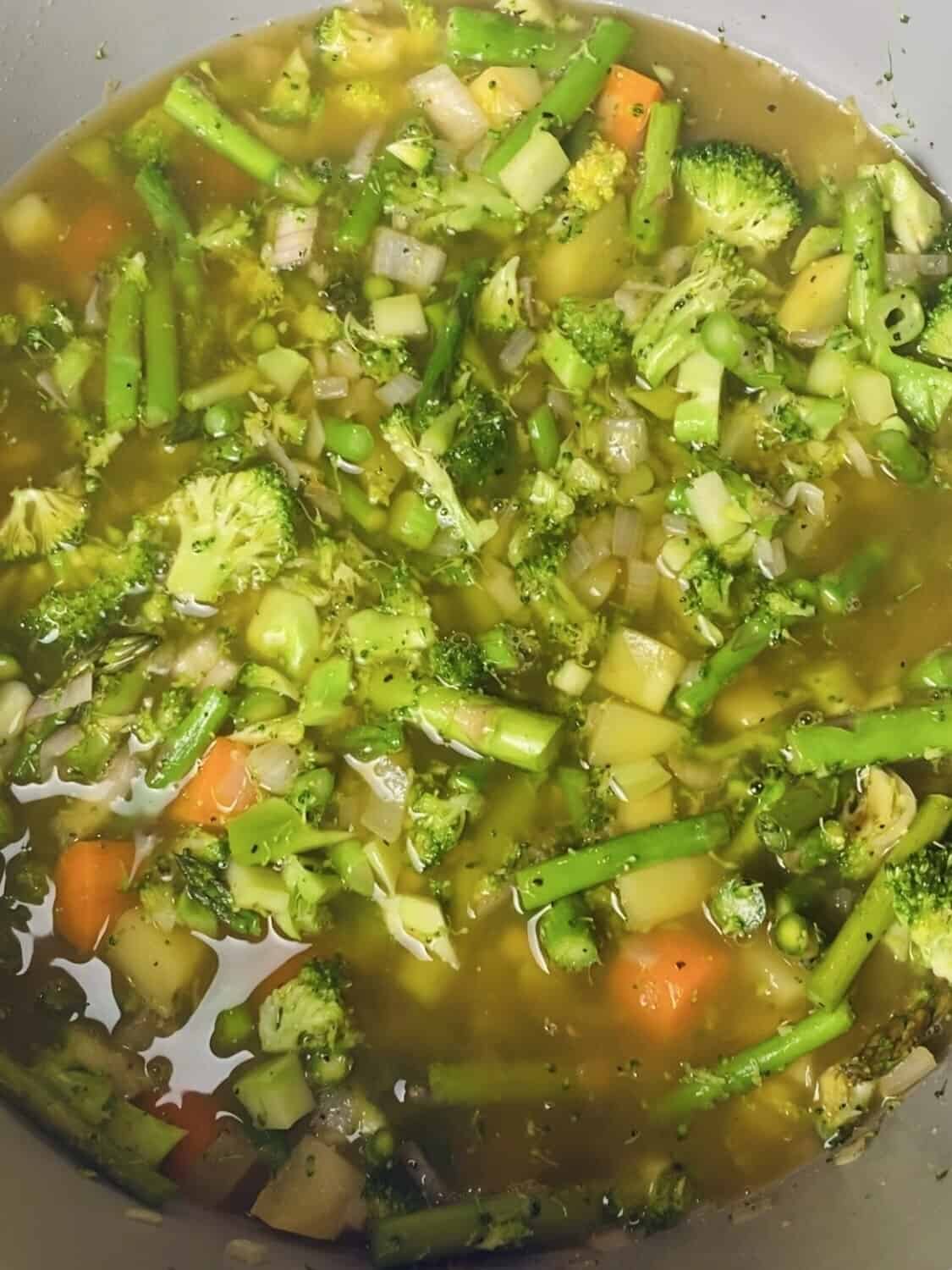 Diced vegetables in vegetable broth in a pot.