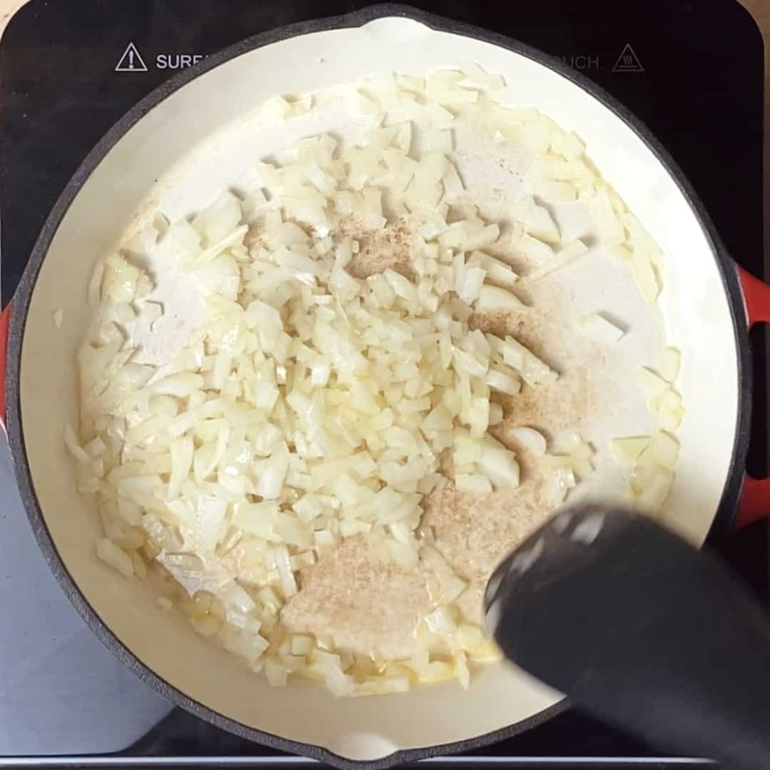 Diced onions being sauteed in a skillet.