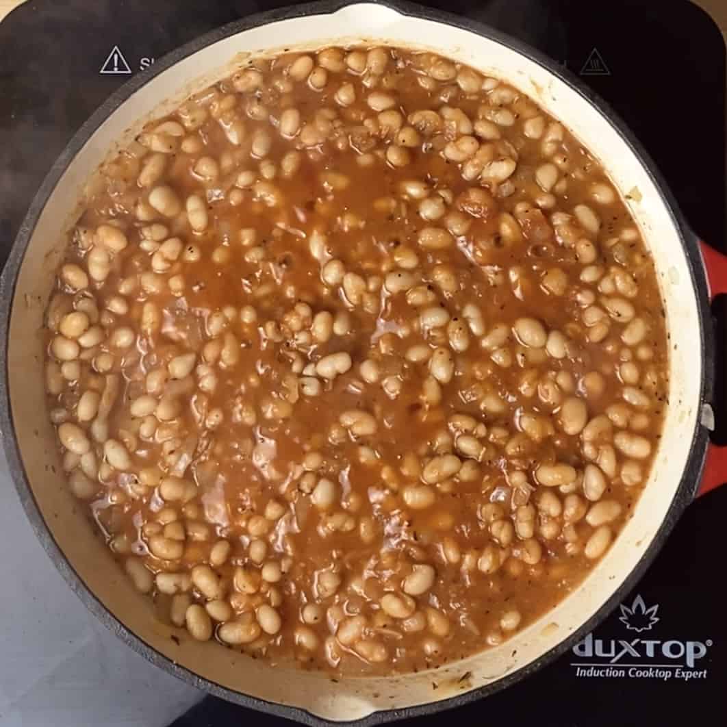 A skillet with the tomato bean mixture sauteeing and bubbling.