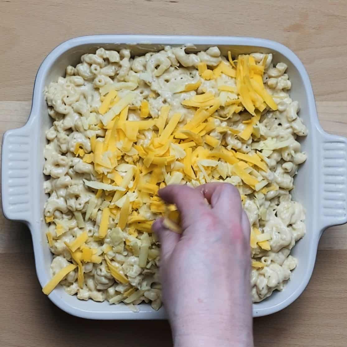 A casserole dish with added cheesy pasta and the rest of the shredded cheese on top.