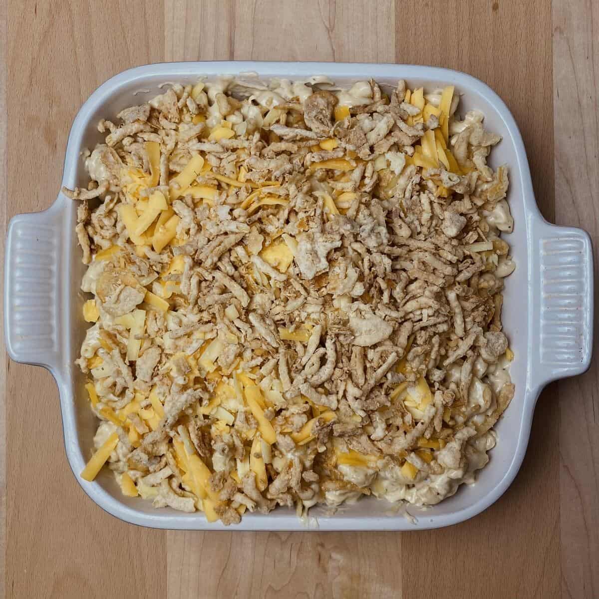 A casserole dish of cheesy mac topped with crispy fried onions.